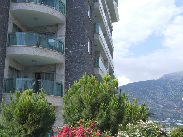 A multi-story building with balconies, surrounded by greenery and mountains in the background. - Graf Victor Hotel (Alanya)
