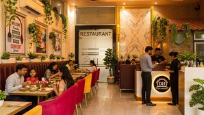 A restaurant interior with red and yellow chairs, a reception desk, and a marble wall. - Dream House Club And Resort (Gonda)