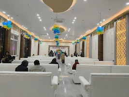 Un salón amplio con filas de sillas blancas, un escenario central con un letrero que dice 'BIENVENIDA, BEBÉ' y globos decorativos.