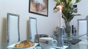 Desayuno con croissant, taza de café, vela y un florero con flores.