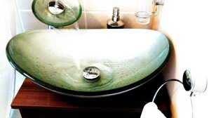 Un lavabo de baño con un recipiente verde, un espejo y un grifo.