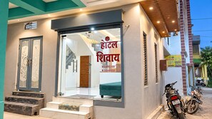 A hotel entrance with a glass door, a staircase, and a motorcycle parked outside. - Hotel Shivay - Near Mahakal Mandir (Ujjain)