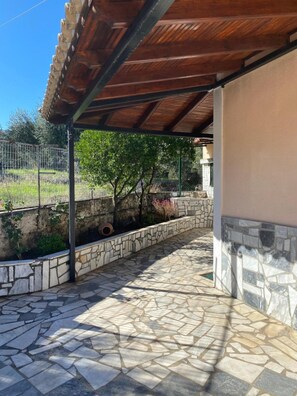 A covered outdoor area with stone flooring, a metal fence, and a stone wall.
