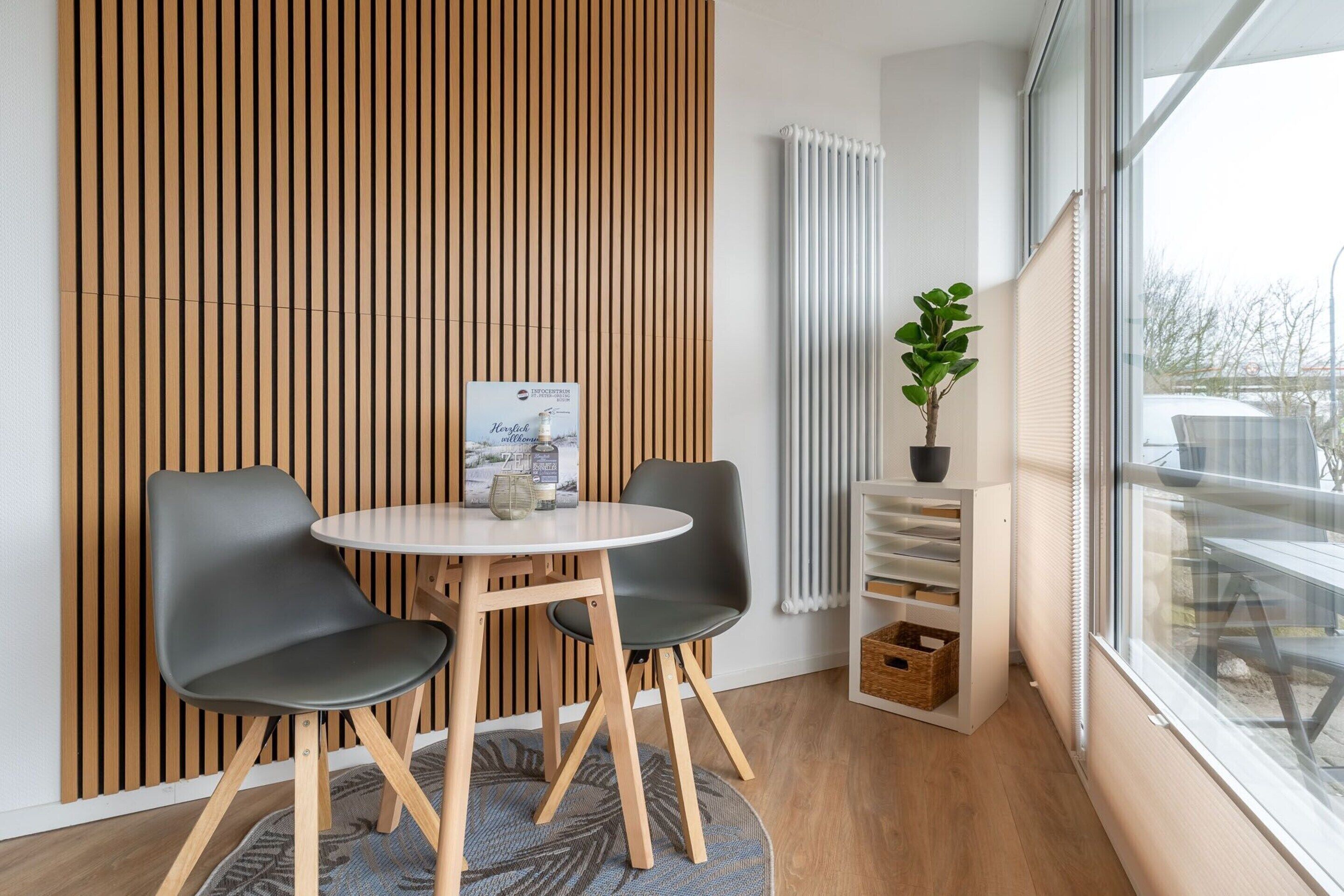 Ein modernes Zimmer mit einem runden Tisch, zwei Stühlen, einem Blumentopf und einer Heizung.