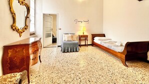 A bedroom with a bed, a nightstand, a mirror, and a door leading to another room. - Dwelling Concept_Art and holiday home_Free parking (Finale Ligure)