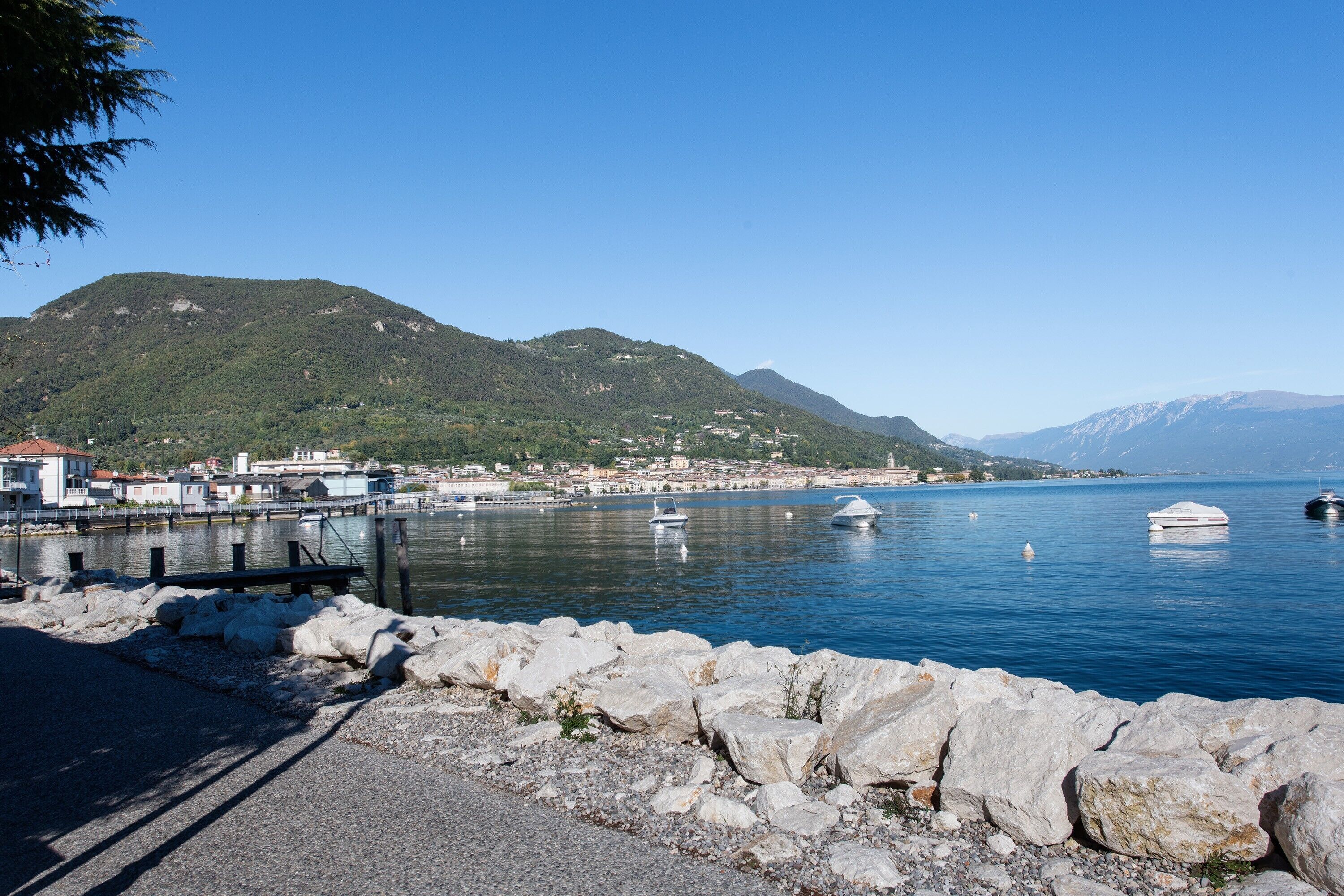 Eine Küstenstadt mit felsiger Küstenlinie, Booten im Wasser und Bergen im Hintergrund.
