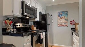 Una cocina moderna con armarios blancos, electrodomésticos de acero inoxidable y un cartel vintage de Steamboat en la pared.