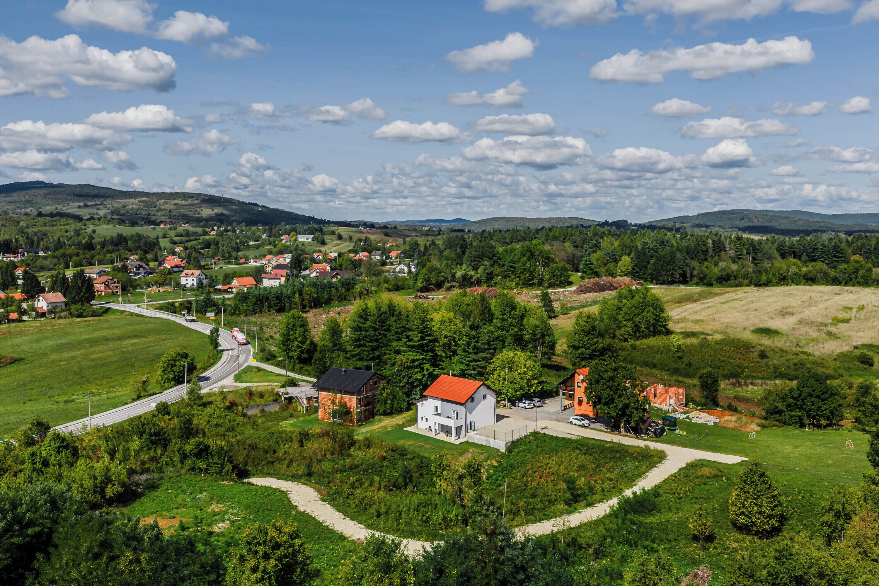 A rural landscape with houses, roads, and greenery.