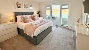 Una camera da letto con un letto grande, un comodino, una cassettiera, una TV e una porta-finestra scorrevole che dà su un balcone.