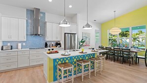 Una cocina moderna con armarios blancos, un refrigerador de acero inoxidable y una isla central con taburetes de bar.