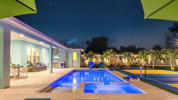 Zona de piscina con sillones de descanso y un espacio de estar cubierto.