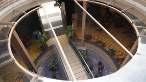 Ein kreisförmiger Innenhof mit einer zentralen Treppe, Blumentöpfen und Sitzbereichen.