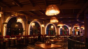 Ein Restaurant mit mehreren Essbereichen, jeweils mit Tischen und Stühlen sowie großen Hängelampen.