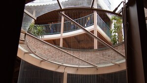 Ein mehrgeschossiges Atrium mit einer Wendeltreppe, Glasgeländern und Pflanzkübeln.