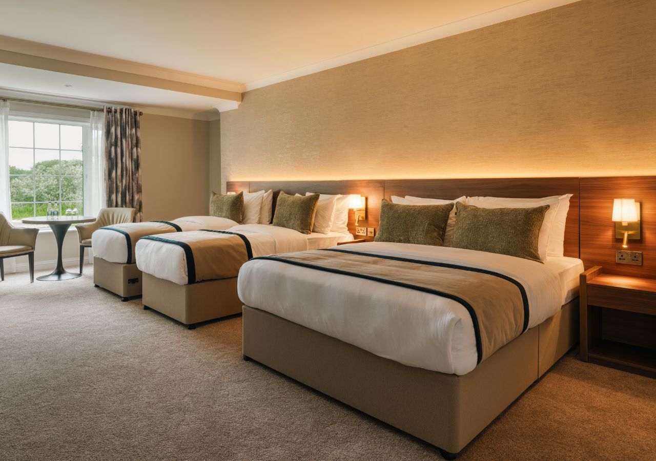 A hotel room with a large bed, a smaller bed, a desk, and a chair.