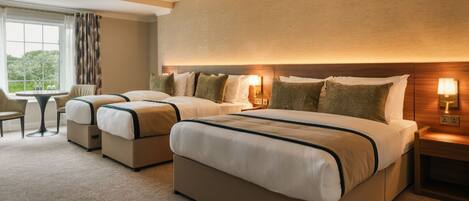 A hotel room with a large bed, a smaller bed, a desk, and a chair.
