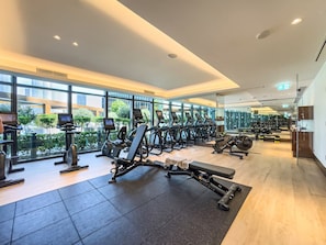 A modern gym with cardio machines, weight benches, and mirrors on the walls.