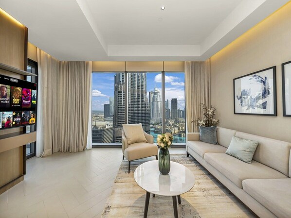 A modern living room with a city view, a sofa, a chair, a coffee table, and a bookshelf.