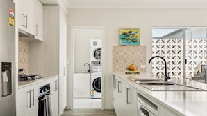A modern kitchen with stainless steel appliances, a built-in oven, and a large sink. - Quenda Villa (Canning Vale)