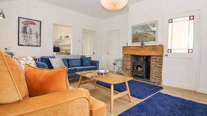 A living room with a sofa, a coffee table, a fireplace, and a blue rug.