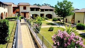 Un patio con varios edificios, un camino central y follaje circundante.