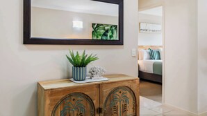 Un mueble de madera con adornos decorativos, un espejo encima y una planta en maceta.