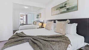 A hotel room with a large bed, a mirror, a painting, and a view of the outside. - Waterfront Bliss Harbour Lights Gym and City View (Cairns City)