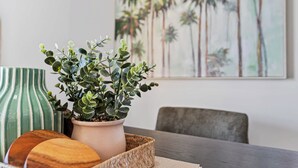 A dining table with a woven tray, a potted plant, and a green vase. - Waterfront Bliss Harbour Lights Gym and City View (Cairns City)