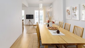 A modern dining area with a wooden table, chairs, a vase with dried plants, and framed botanical prints on the wall. - Bel Air by halu (Thessaloniki)