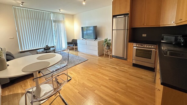 Una cocina moderna con armarios de madera, un refrigerador de acero inoxidable y un horno empotrado.