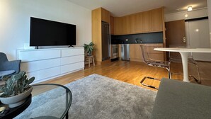 Una sala de estar moderna con un televisor de pantalla plana, una mesa de centro de vidrio y un sofá gris.