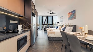 A modern hotel room with a kitchen, dining area, and a large bed.