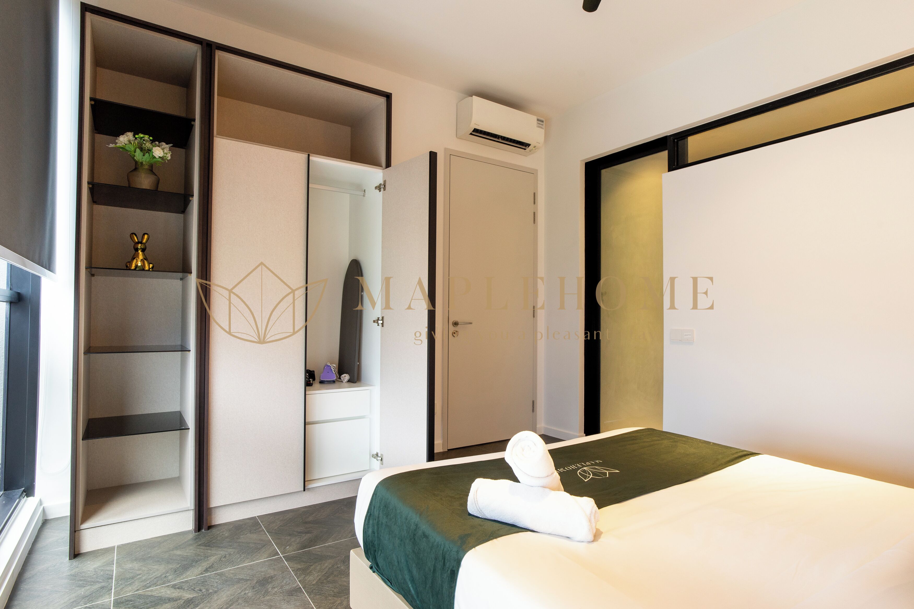 Een hotelkamer met een bed, een kledingkast, een plank met decoratieve objecten en een airconditioning.