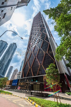 En moderne skyskraber med en unik geometrisk facade, beliggende i en bymidte omgivet af andre høje bygninger.