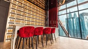 A bar area with a city view, a large wine rack, and red bar stools.