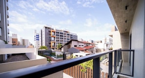 A residential building with balconies, a swimming pool, and a view of other buildings.