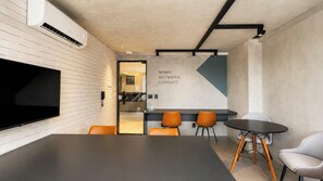 Una sala de reuniones moderna con una gran pantalla plana, una mesa de conferencias y varias sillas.