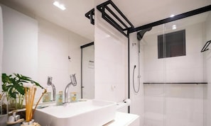 A modern bathroom with a white sink, mirror, and glass shower enclosure.