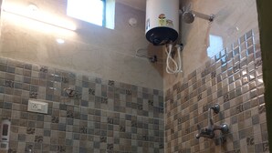 Un baño con piso de baldosas, un lavamanos, un inodoro, una ducha y un calentador de agua.