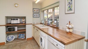Une cuisine compacte équipée d’un lave-linge, d’un four à micro-ondes et d’un plan de travail en bois.