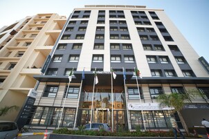 A multi-story hotel with a modern facade, large windows, and a prominent entrance with flags.