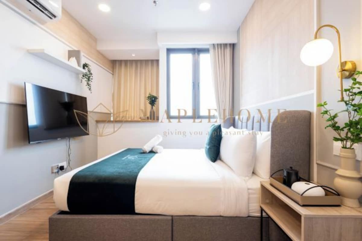 Une chambre d’hôtel moderne équipée d’un lit, d’une télévision, d’une table de chevet avec une lampe et d’une fenêtre avec des rideaux.
