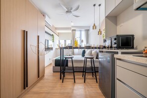 Una cocina moderna con una isla central, dos taburetes de bar, un refrigerador y un ventilador de techo.