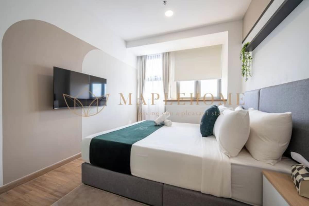 Une chambre d’hôtel moderne équipée d’un lit, d’un téléviseur à écran plat fixé au mur et d’une fenêtre avec des rideaux.