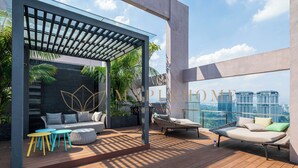 Eine Dachterrasse mit einer Pergola, einer Sitzecke und Blick auf die Skyline der Stadt.