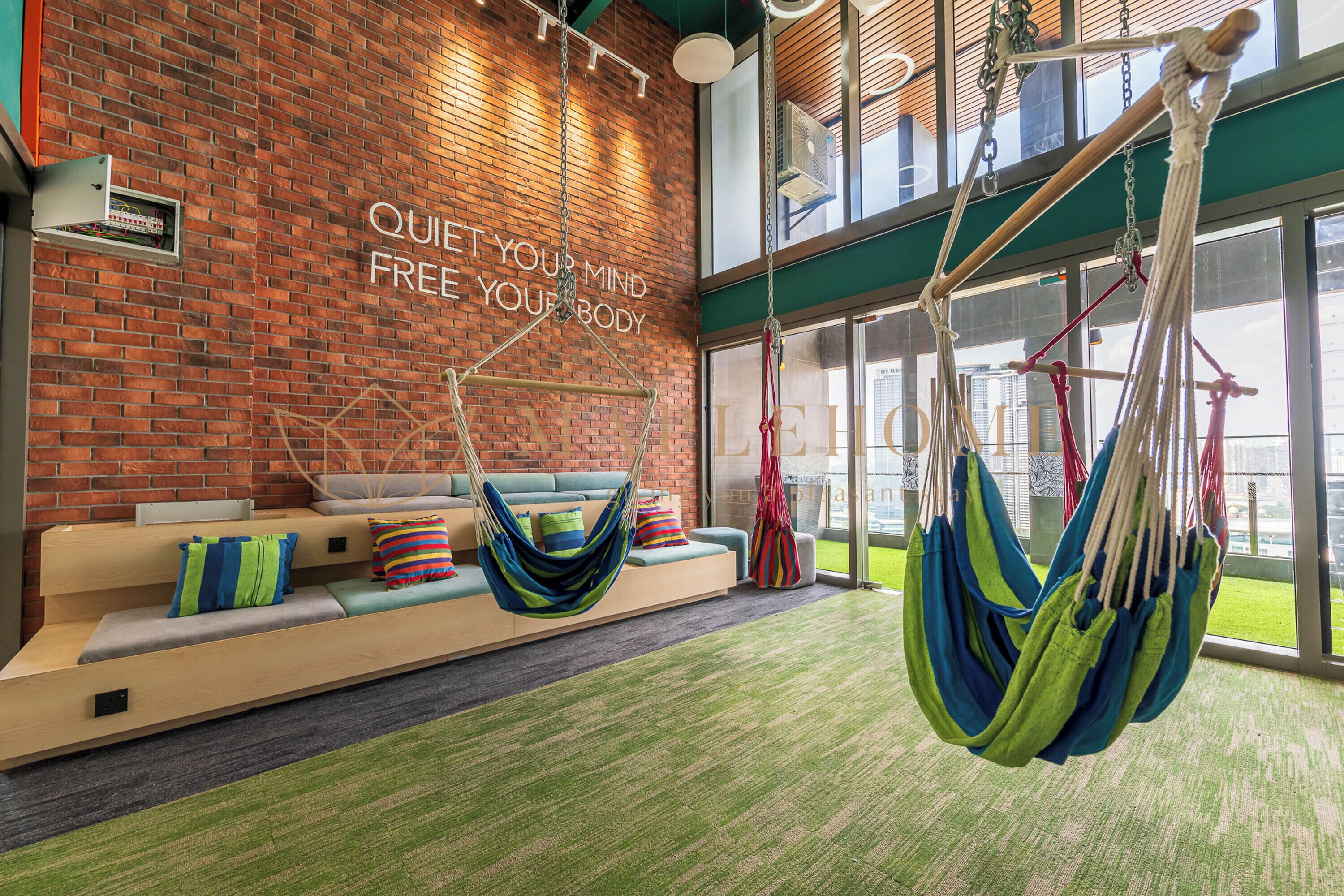 A modern lounge area with a brick wall, a sofa with colorful cushions, and hammocks.