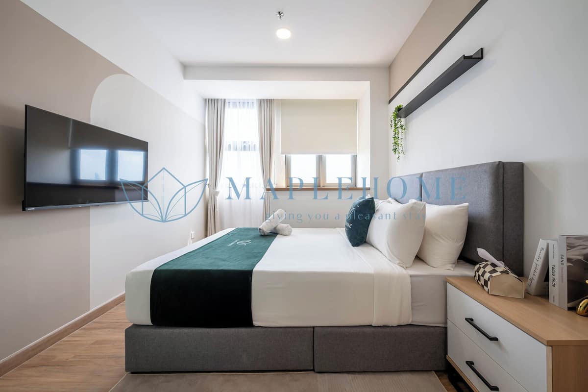 Un dormitorio moderno con cama, mesita de noche y televisor de pantalla plana montado en la pared.