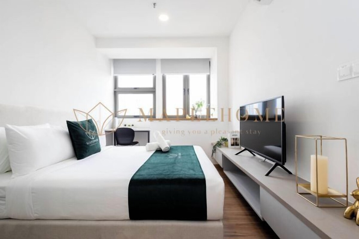 Une chambre d’hôtel moderne équipée d’un lit, d’une télévision et d’une fenêtre laissant entrer la lumière naturelle.