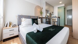 Ein modernes Hotelzimmer mit einem ordentlich bezogenen Bett, einem Schreibtisch und einer Küchenzeile.