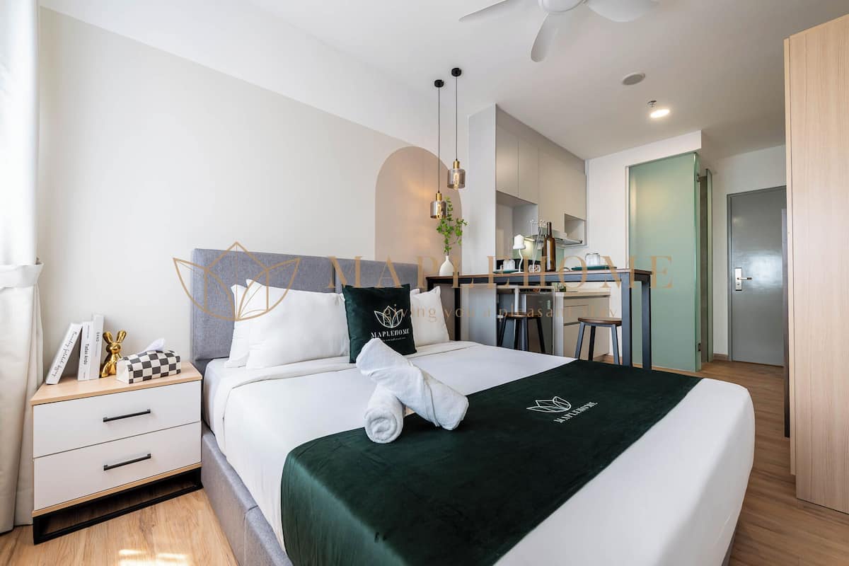 Una habitación de hotel moderna con una cama bien hecha, un escritorio y una kitchenette.